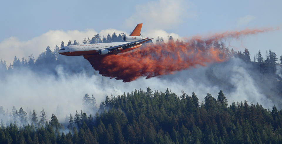 FILE - In this Aug. 21, 2015 file photo, a tanker airplane drops fire retardant on a wildfire burning near Twisp, Wash. Newly released national plans for fighting wildfires during the coronavirus pandemic are hundreds of pages long but don't offer many details on how fire managers will get access to COVID-19 tests or exactly who will decide when a crew needs to enter quarantine. (AP Photo/Ted S. Warren, File)