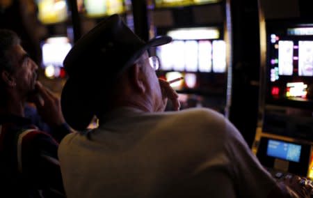 FILE PHOTO: A man smokes as he plays a slot machine at the Island View Casino in Gulfport, Mississippi November 9, 2009. REUTERS/Carlos Barria