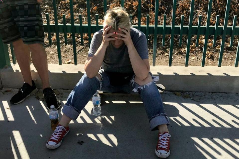 An unidentified woman sits next to witnesses outside the scene at a Trader Joe's in L.A.'s Silver Lake neighborhood after a gunman took hostages there on Saturday, according to police.