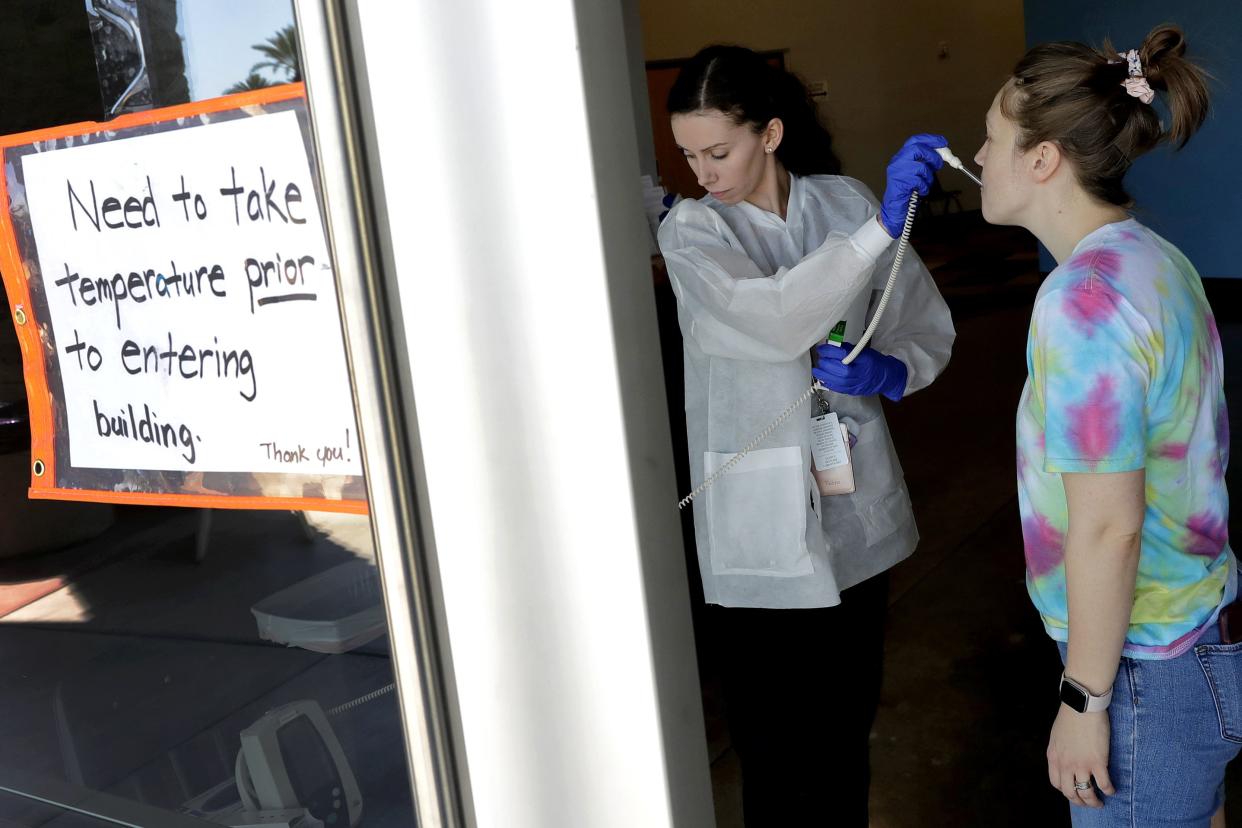 Emily Miles has her temperature taken before being allowed to donate blood at a temporary blood bank set up in a church's fellowship hall Tuesday, March 24, 2020, in Tempe, Ariz. Schools and businesses that typically host blood drives are temporarily closed due to precautionary measures in place to reduce the spread of the COVID-19 coronavirus leading to extremely low levels of blood availability throughout the state.