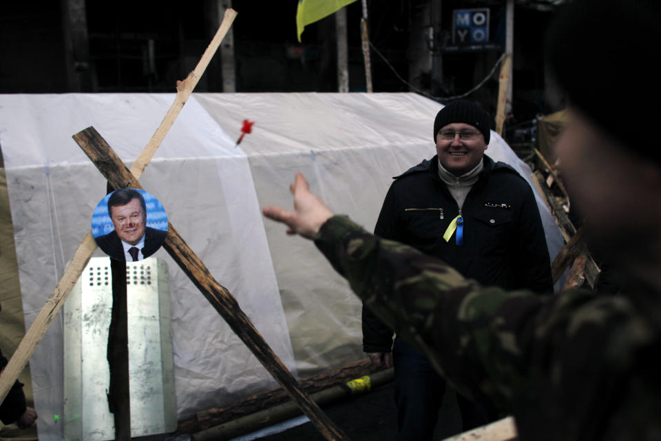 A portrait of Ukraine's President Viktor Yanukovych is used for a game of darts at Independence Square in Kiev, Ukraine, Monday, Feb. 24, 2014. Ukraine's acting government issued an arrest warrant Monday for Yanukovych, accusing him of mass crimes against the protesters who stood up for months against his rule. Russia sharply questioned its authority, calling it an "armed mutiny." Yanukovych himself has reportedly fled to the Black Sea peninsula of Crimea, a pro-Russian area in Ukraine. (AP Photo/ Marko Drobnjakovic)