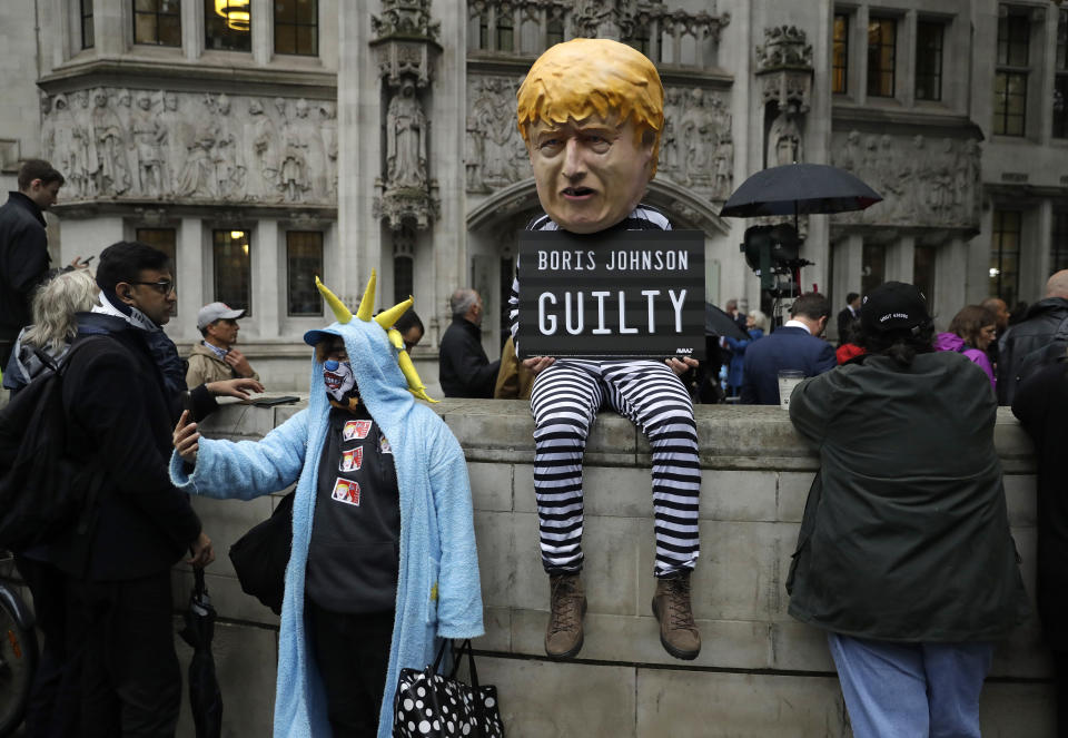 A person dressed as a caricature of British Prime Minister Boris Johnson in a prison uniform stands outside the Supreme Court in London, Tuesday, Sept. 24, 2019 after it made it's decision on the legality of Johnson's five-week suspension of Parliament. In a setback for Johnson, Britain's Supreme Court has ruled that the suspension of Parliament was illegal. The ruling Tuesday is a major blow to the prime minister who had suspended Parliament for five weeks, claiming it was a routine closure. (AP Photo/Matt Dunham)