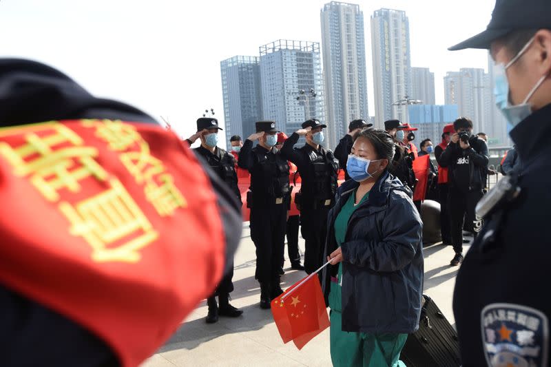 Police officers salute as a medical worker from outside Wuhan arrives at the Wuhan Railway Station before leaving the epicentre of the novel coronavirus disease outbreak
