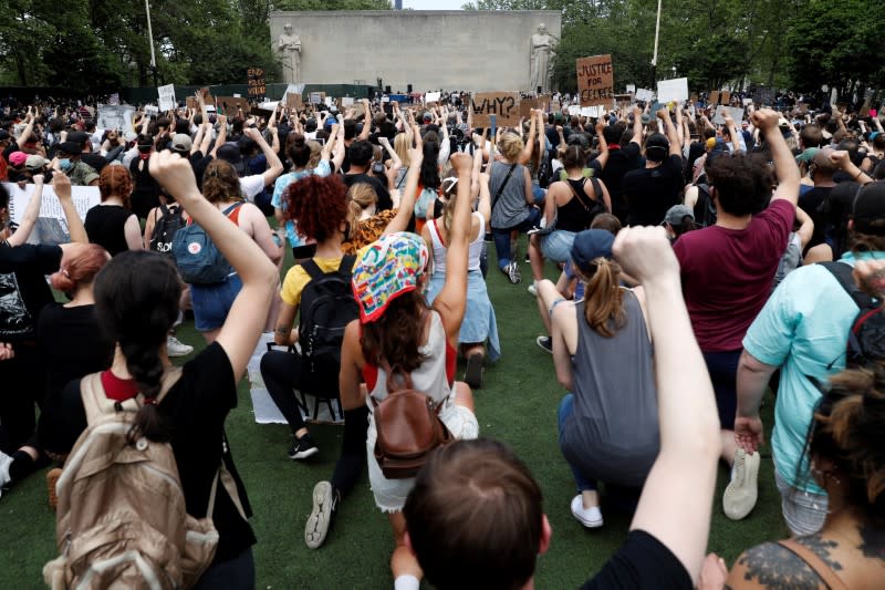 Personas se arrodillan y levantan los puños mientras asisten a un servicio conmemorativo público después de la muerte en custodia policial de George Floyd en Mineápolis, EEUU