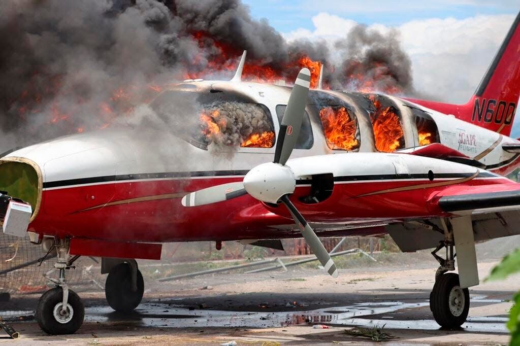 A plane burns after being set on fire by demonstrators protesting increasing violence at the Antoine Simon Des Cayes airport in Les Cayes, Haiti, Tuesday, March 29, 2022. The protest coincides with the 35th anniversary of Haiti's 1987 Constitution and follows other protests and strikes in recent weeks in the middle of a spike in gang-related kidnappings.