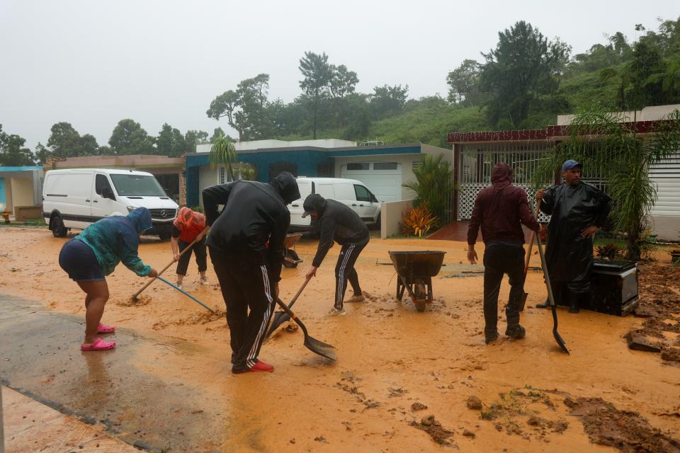 People clean debris from a road after a mudslide caused by Hurricane Fiona in Cayey, Puerto Rico, Sunday, 18 September 2022 (AP)