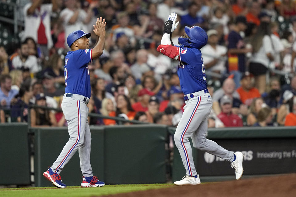 Texas Rangers' Adolis Garcia, right, celebrates with third base coach Tony Beasley after hitting a home run against the Houston Astros during the fifth inning of a baseball game Tuesday, Aug. 9, 2022, in Houston. (AP Photo/David J. Phillip)