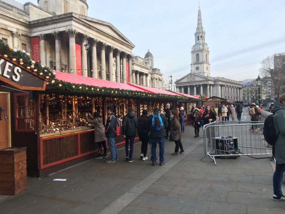 Visitors to Trafalgar Square take a look at the Christmas market stalls.