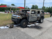 In this photo provided by Citrus County Fire Rescue an officer stands near a Hummer which was destroyed by fire shortly after the driver had filled up four 5-gallon (18-liter) gas containers on Wednesday, May 12, 2021, in Homosassa, Fla. Many authorities are warning of the dangers of hoarding gas as shortages at the pumps are spreading from the South to the Mid-Atlantic states, following a cyberattack that forced a shutdown of the nation’s largest gasoline pipeline. (Citrus County Fire Rescue via AP)