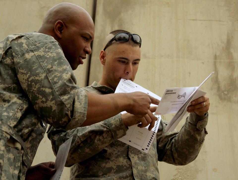 U.S. Army Cpl. Sean Morton, 25, of Boston consults with a colleague before mailing his absentee ballot for the presidential election at Forward Operating Base Marez in Mosul, Iraq, on Oct. 22, 2008.