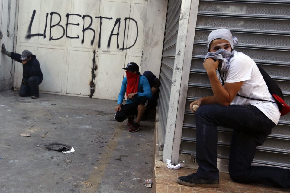 Anti-government protesters react to teargas during clashes at Altamira square in Caracas