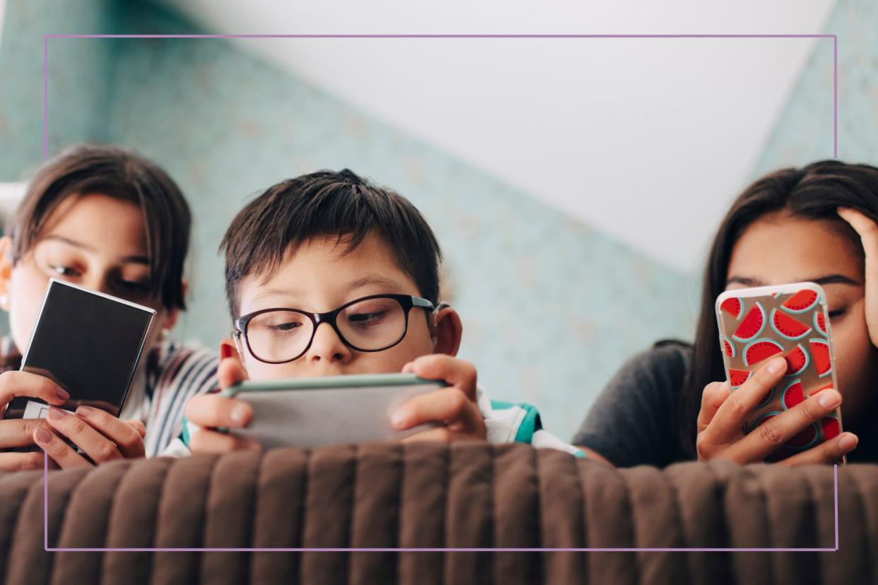  Three kids lying on bed using phones. 