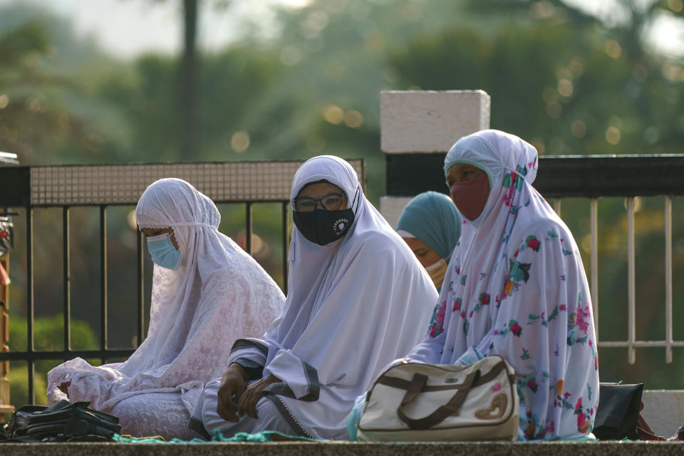 Muslim women wearing protective masks wait to pray outside the National Mosque while celebrating Eid al-Fitr, the Muslim festival marking the end the holy fasting month of Ramadan in Kuala Lumpur, Malaysia, Thursday, May 13, 2021. (AP Photo/Vincent Thian)