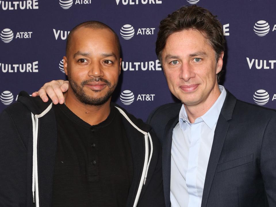 Donald smiling in a black shirt and blazer and Zach smiling with his arm around Donald in a blue shirt and blazer.