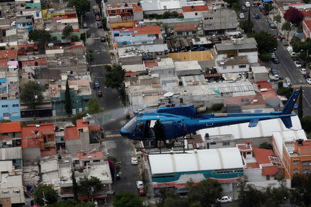 Police officers, members of a team known as "Condores", stand by the door of the helicopters during a patrol of the city, part of a new strategy to combat the crime in Mexico City, Mexico August 3, 2018. Picture taken August 3, 2018. REUTERS/Carlos Jasso