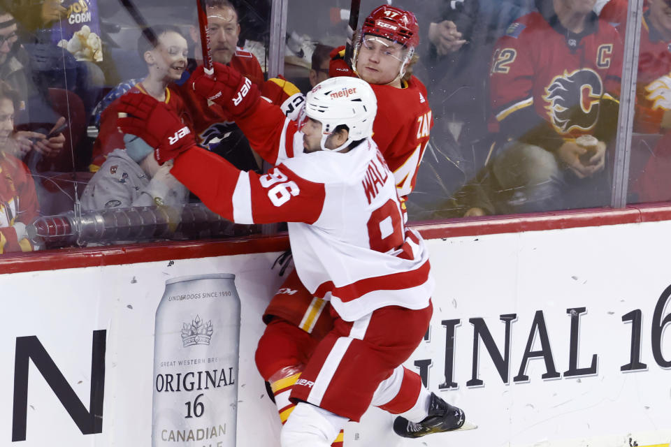 Detroit Red Wings' Jake Walman, front checks Calgary Flames' Connor Zary, right, during the first period of an NHL hockey game in Calgary, Alberta, Saturday, Feb. 17, 2024. (Larry MacDougal/The Canadian Press via AP)