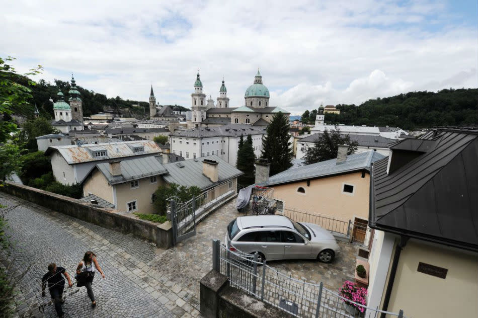 In front of the backdrop of the steeples of St. Peters convent (L), Franciscan church and Salzburg cathedral tourists walk up the old way to Salzburg castle Hohensalzburg.