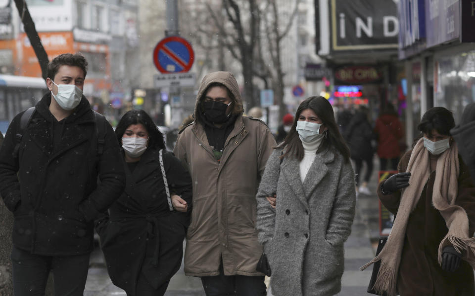 People wearing masks to help protect against the spread of the coronavirus walk in Ankara, Turkey, Friday, March 26, 2021. Daily COVID-19 infections in Turkey surged above 26,000 on Friday, weeks after the government eased restrictions in dozens of provinces under a so-called "controlled normalization" program. (AP Photo/Burhan Ozbilici)
