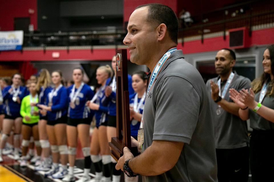 Barron Collier coach Yamil Del Valle accepts the runner-up trophy after their game against Jensen Beach in the FHSAA Class 5A volleyball state championship on Saturday, Nov. 12, 2022, at Polk State College in Winter Haven.