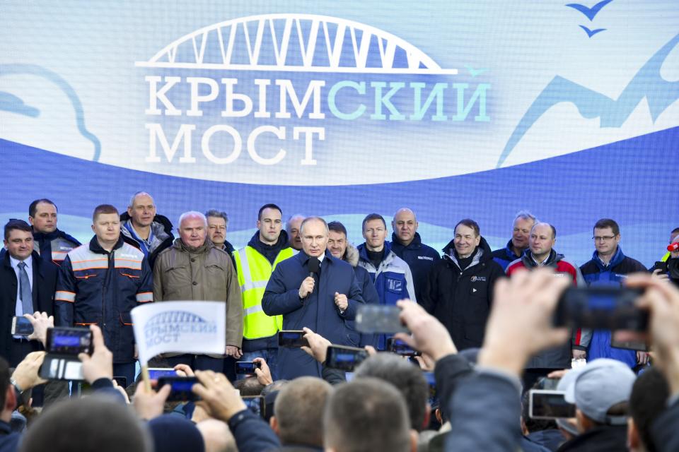 Russian President Vladimir Putin, center, speaks to workers after riding a train across a bridge linking Russia and the Crimean peninsula in Taman, Russia, Monday, Dec. 23, 2019. Putin on Monday inaugurated a railway bridge to Crimea, the longest in Europe, which is intended to facilitate links with Crimea, which Russia annexed from Ukraine in 2014. (AP Photo)