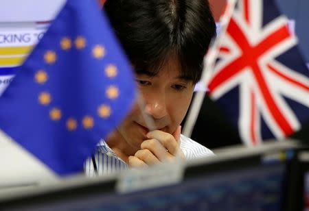 An employee of a foreign exchange trading company works between a British flag and an EU flag in Tokyo, Japan, June 24, 2016. REUTERS/Issei Kato