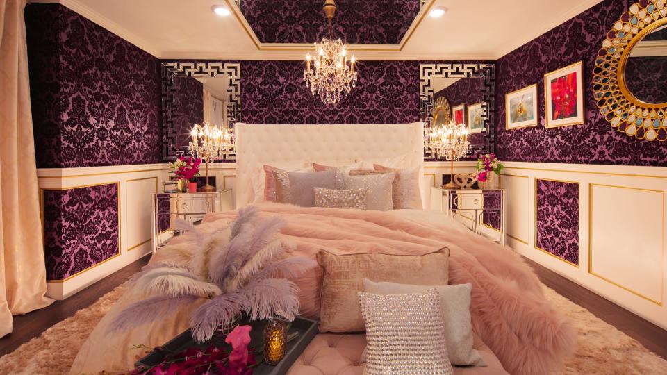 One of the sex rooms created by Melanie Rose, which shows a bed with lots of pillows, throws, and mirrors on the wall.