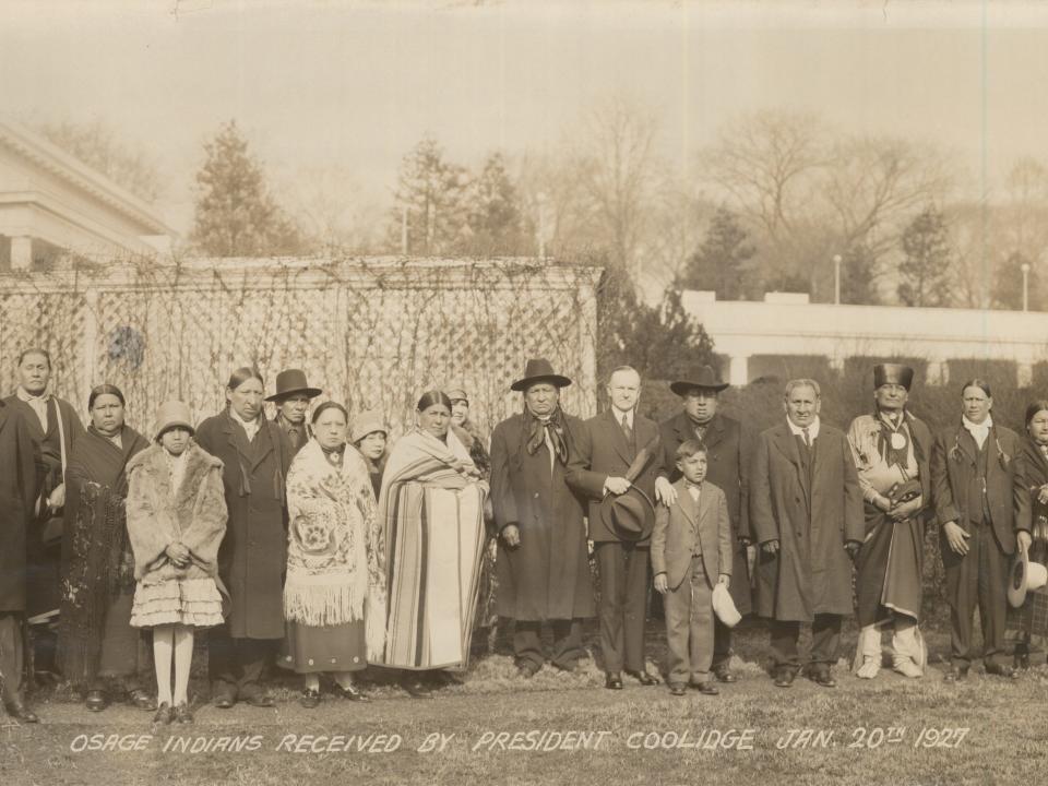 Portrait of US President Calvin Coolidge (1872 - 1933) (center right, with hat in hand) and unidentified representatives from the Osage Nation as they pose in front of the East Colonnade at the White House, Washington DC, January 20, 1927