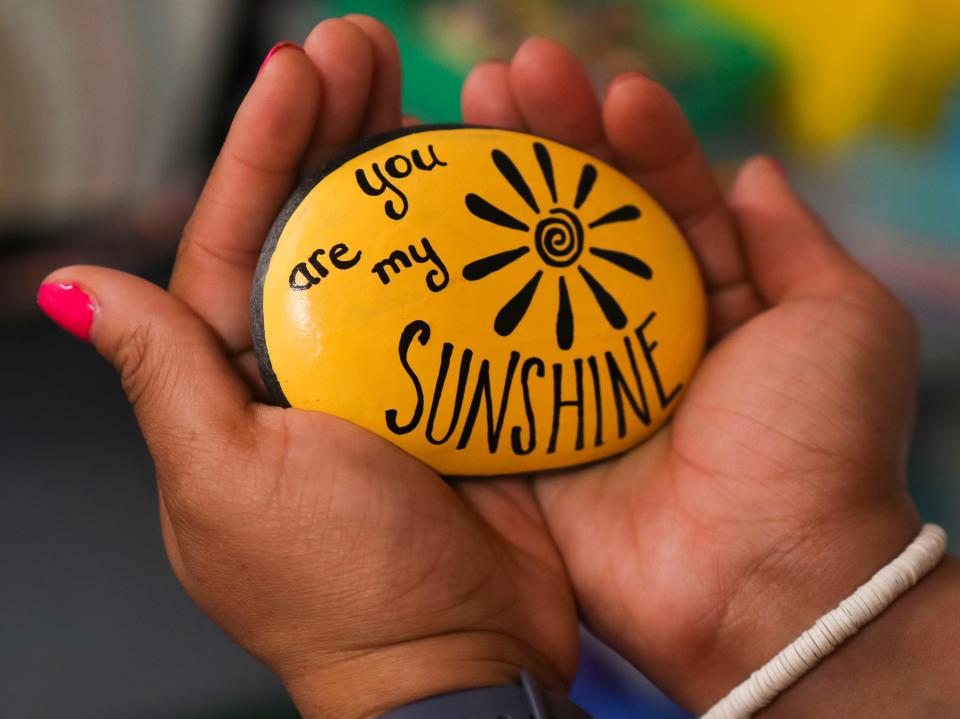 Tahiya Cooper, a school counselor at Holly Hall Elementary School in Elton, Maryland, holds a stone painted in the fashion of the title subject in her children's book "The Sunshine Rock," Tuesday, May 16, 2023.