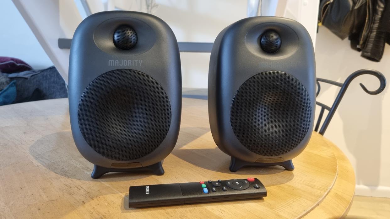  The Majority D80 Active Bluetooth Speakers on a wooden table with the included remote. 