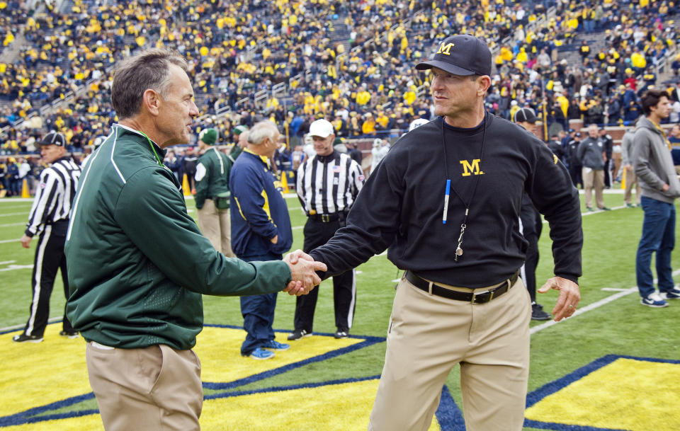 FILE - In this Oct. 17, 2015, file photo, Michigan State head coach Mark Dantonio shakes hands with Michigan head coach Jim Harbaugh on the Michigan Stadium field before an NCAA college football game in Ann Arbor, Mich. Sixth-ranked Michigan has won six straight and is in the top 10 for the first time this season. The Wolverines need to beat rival Michigan State this Saturday to keep the roll going. (AP Photo/Tony Ding, FIle)