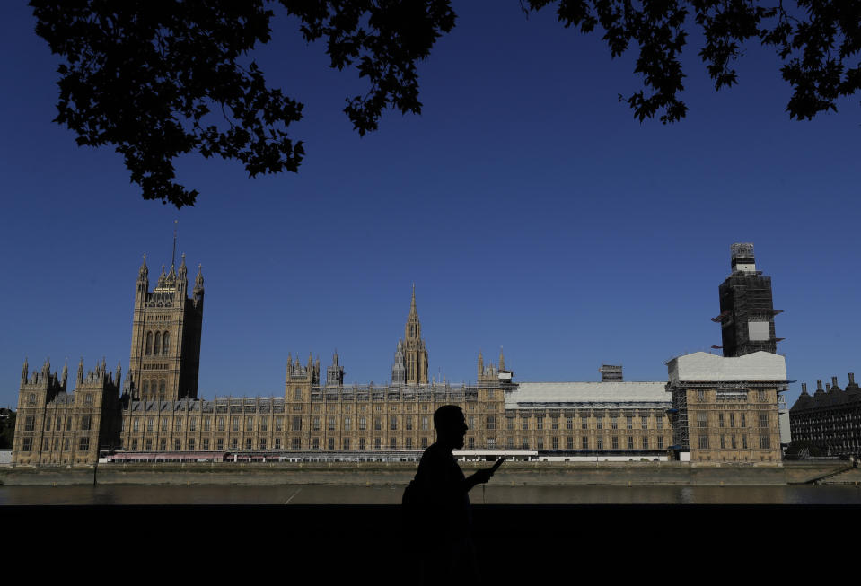 A pedestrian passes Britain's Houses of Parliament on the bank of The River Thames in London, Thursday, Aug. 29, 2019. Jacob Rees-Mogg, The leader of the British House of Commons has defended Prime Minister Boris Johnson's move to suspend parlliament, a move that gives his political opponents less time to block a no-deal Brexit before the October 31 withdrawal deadline. (AP Photo/Kirsty Wigglesworth)