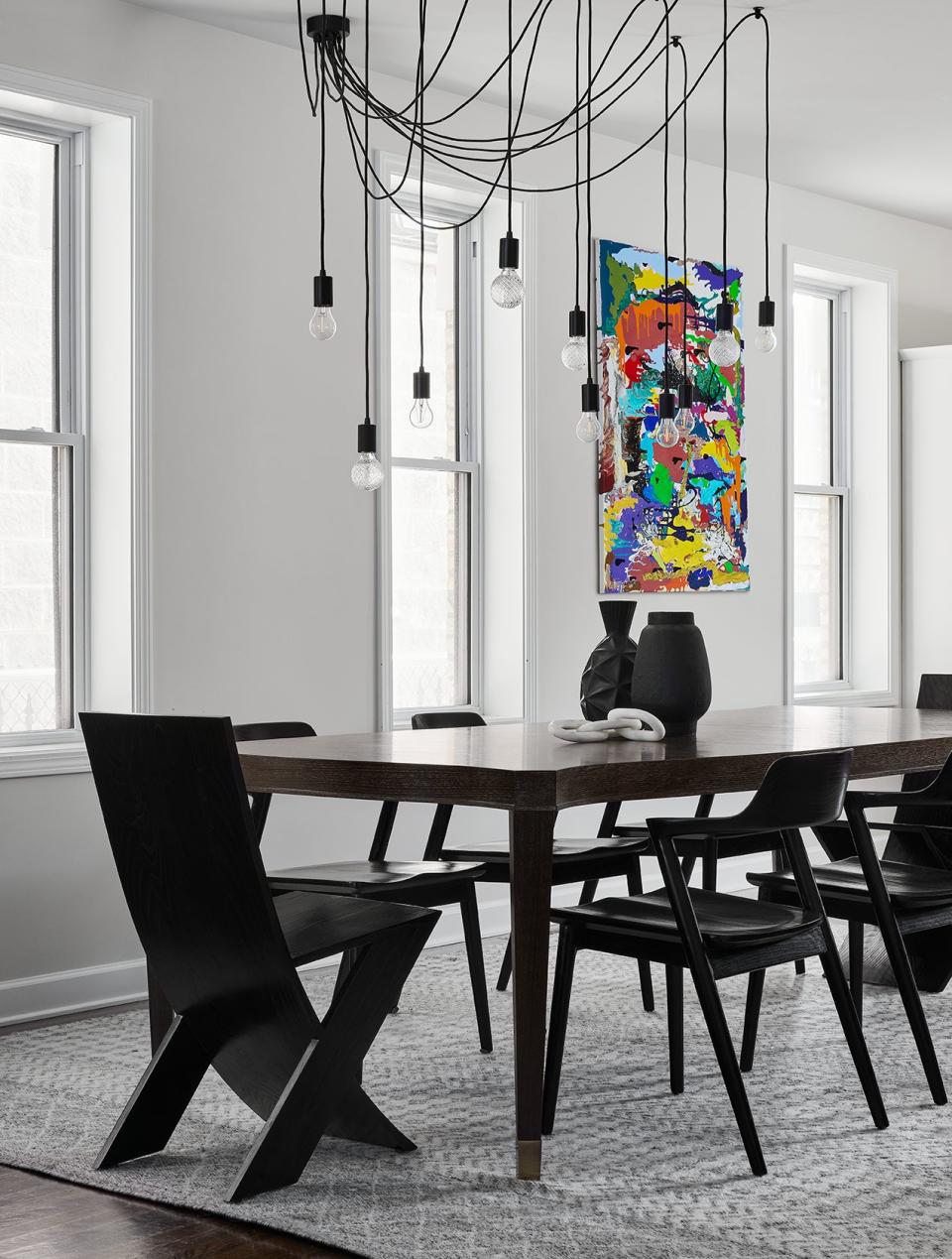 In this black-and-white dining room, Paula Interiors added a brightly colored artwork for contrast.