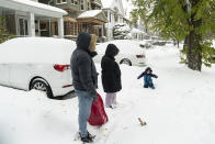 Auggie Rokitka, 2, plays in the snow with his parents, Matt Rokitka and Krissy Godios, on Richmond Avenue in Buffalo, N.Y. Saturday, Nov. 19, 2022. Residents of northern New York state are digging out from a dangerous lake-effect snowstorm that had dropped nearly 6 feet of snow in some areas and caused three deaths. The Buffalo metro area was hit hard, with some areas south of the city receiving more than 5 feet by early Saturday. (Libby March /The Buffalo News via AP)