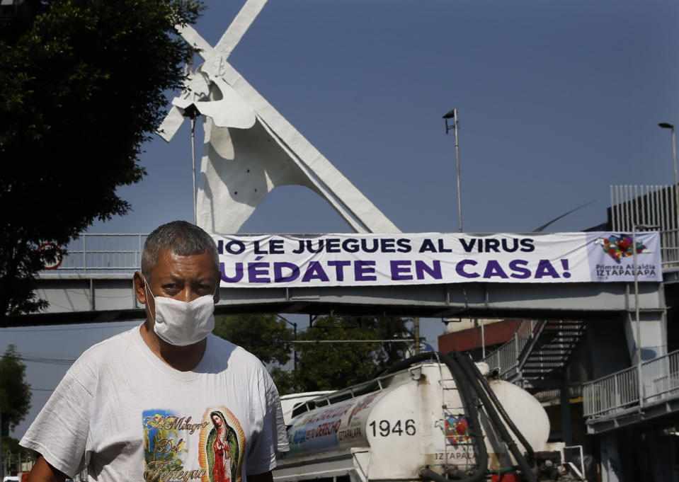 A man walk past a banner that reads in Spanish "Don't play with your life. Stay home," as he wears a mask against the spread of the new coronavirus in Mexico City, Thursday, April 9, 2020. The Mexico City government is sending out teams to help the home-bound and the homeless during the shutdown declared to combat the coronavirus. (AP Photo/Marco Ugarte)