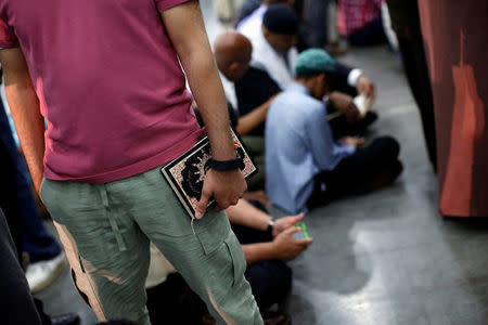 A man holds the Koran as he arrives to attend the jenazah prayer, an Islamic funeral prayer, for late boxing champion Muhammad Ali in Louisville, Kentucky, U.S. June 9, 2016. REUTERS/Carlos Barria