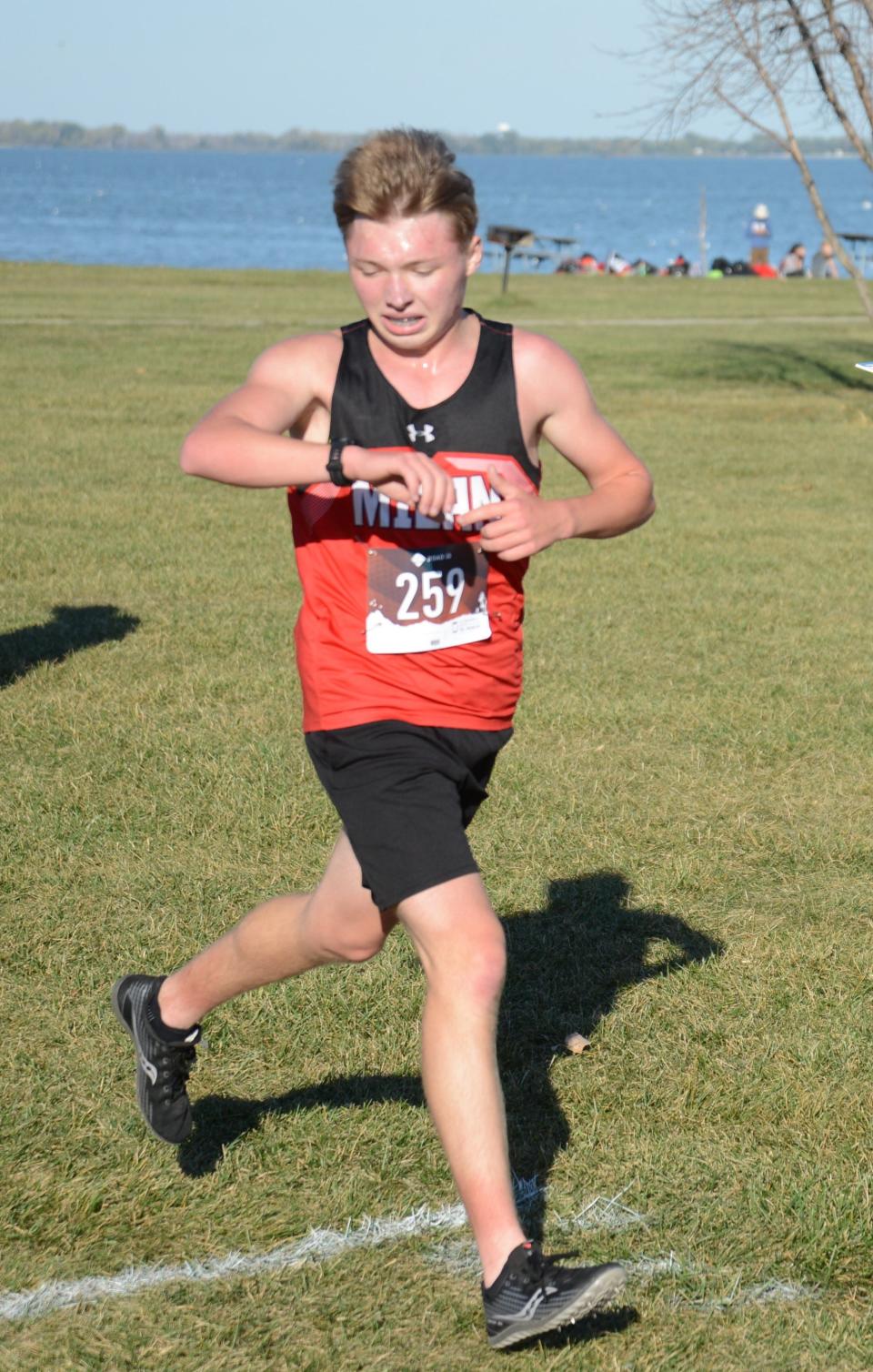 Parker Prior of MIlan checks his watch as he runs in the Huron League jamboree at Sterling State Park Tuesday.