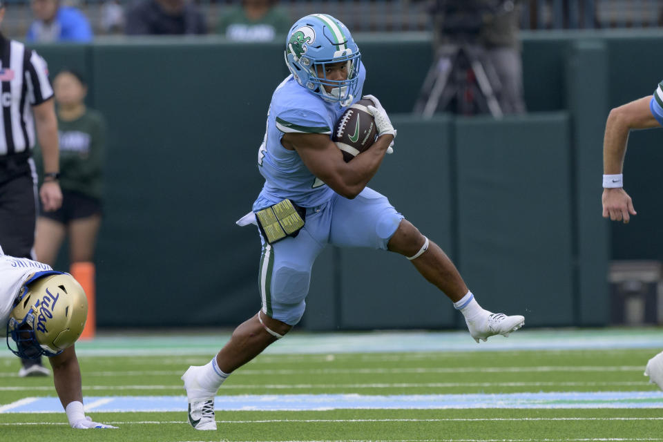 FILE - Tulane running back Makhi Hughes (21) runs during an NCAA college football game against Tulsa, Nov. 11, 2023, in New Orleans. Tulane and Virginia Tech meet Wednesday, Dec. 27, 2023, in Annapolis, Md., for the Military Bowl. The game will take place at Navy's home stadium, and although Tulane is in the same conference as the Midshipmen, the Green Wave haven't played there since 2019. (AP Photo/Matthew Hinton, File)