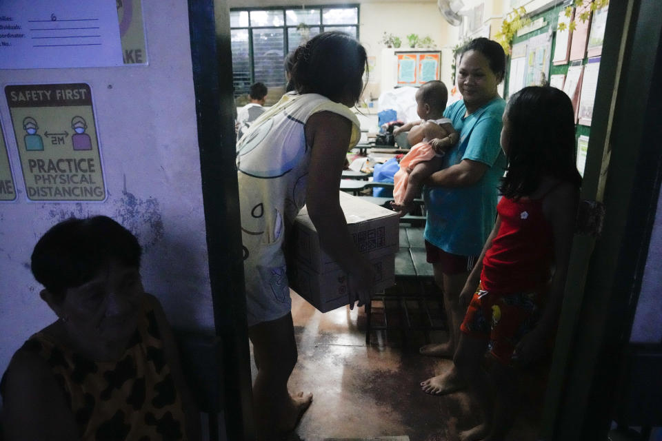 An evacuee carries relief goods at an evacuation center at Santo Domingo town, Albay province, northeastern Philippines, Tuesday, June 13, 2023. Truckloads of villagers on Tuesday fled from Philippine communities close to gently erupting Mayon volcano, traumatized by the sight of red-hot lava flowing down its crater and sporadic blasts of ash. (AP Photo/Aaron Favila)