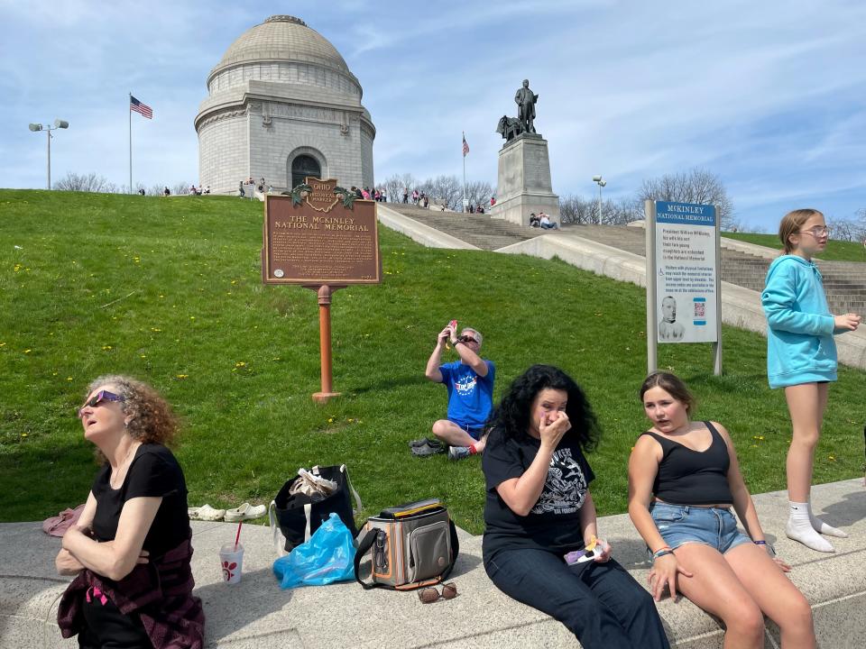 About 100 people of all ages, scattered about the lawn, steps and railing at Canton’s McKinley Monument on Monday afternoon to view the solar eclipse.