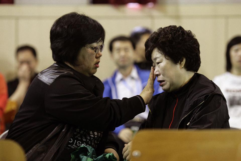 Relatives of a missing student weep while they comfort each others at auditorium in Danwon High School in Ansan, South Korea, Thursday, April 17, 2014. Strong currents, rain and bad visibility hampered an increasingly anxious search Thursday for 287 passengers, including many students from the high school for a four-day trip, still missing a day after their ferry flipped onto its side and sank in cold waters off the southern coast of South Korea. (AP Photo/Woohae Cho