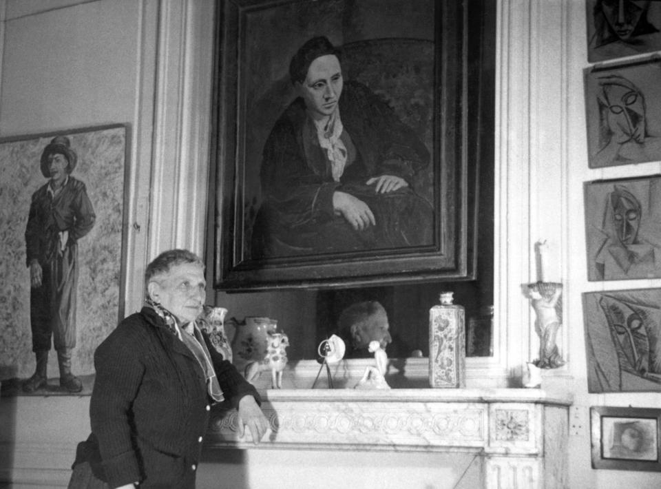 American writer Gertrude Stein (1874-1946), posing with a portrait of herself painted by Picasso in 1906