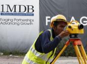 A construction worker works in front of a 1Malaysia Development Berhad (1MDB) billboard at the Tun Razak Exchange development in Kuala Lumpur, Malaysia February 3, 2016. REUTERS/Olivia Harris/File Photo