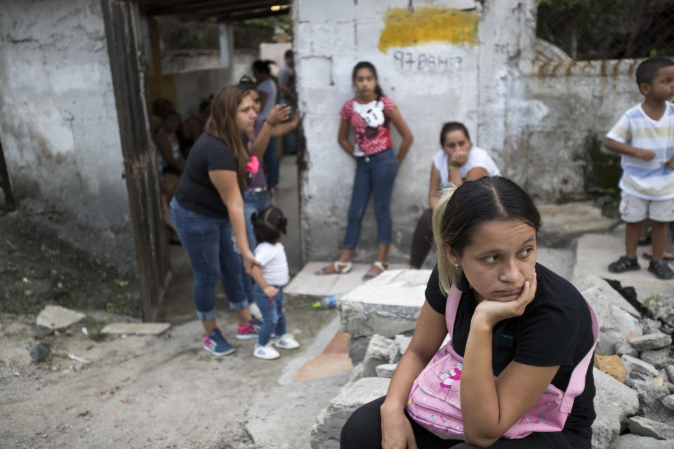 In this Oct. 31, 2018 photo, relatives who attended the burial service of Wilmer Gerardo Nunez wait for a bus to transport them home, at a cemetery in San Pedro Sula, Honduras. About a week after Nunez left Honduras for the last time, he spoke to his mother, telling her to pray that everything would turn out well. A few weeks after that call Nunez disappeared. (AP Photo/Moises Castillo)