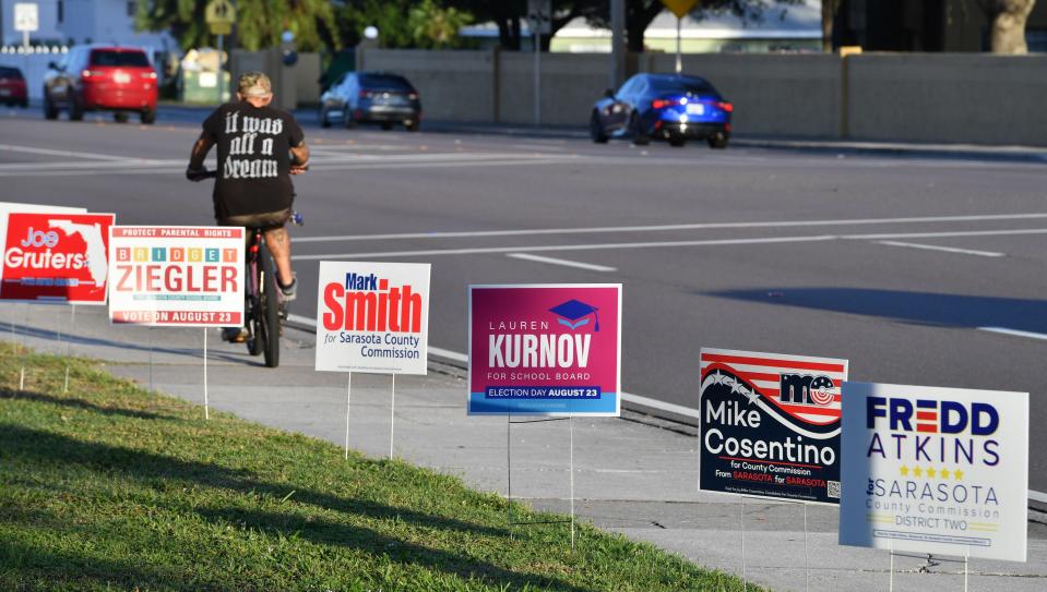 A cyclist rides past candidate campaign signs lining Bee Ridge Road outside the polling place at Church of the Palms in Sarasota on Primary Election Day on Tuesday morning, Aug. 23, 2022.