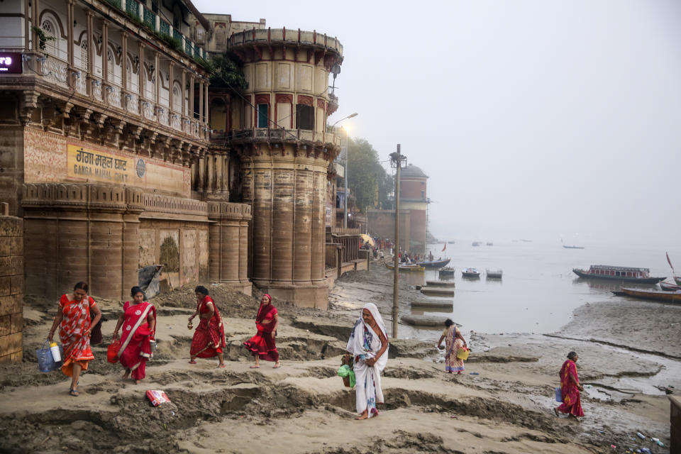 Hindu women walk on silt, deposited by monsoon floods, along the banks of the river Ganges to perform daily morning rituals in Varanasi, one of the Hinduism's holiest cities, in the northern Indian state of Uttar Pradesh, Friday, Oct. 18, 2019. For millions of Hindus, Varanasi is a place of pilgrimage and anyone who dies in the city or is cremated on its ghats is believed to attain salvation and freed from the cycle of birth and death. (AP Photo/Altaf Qadri)