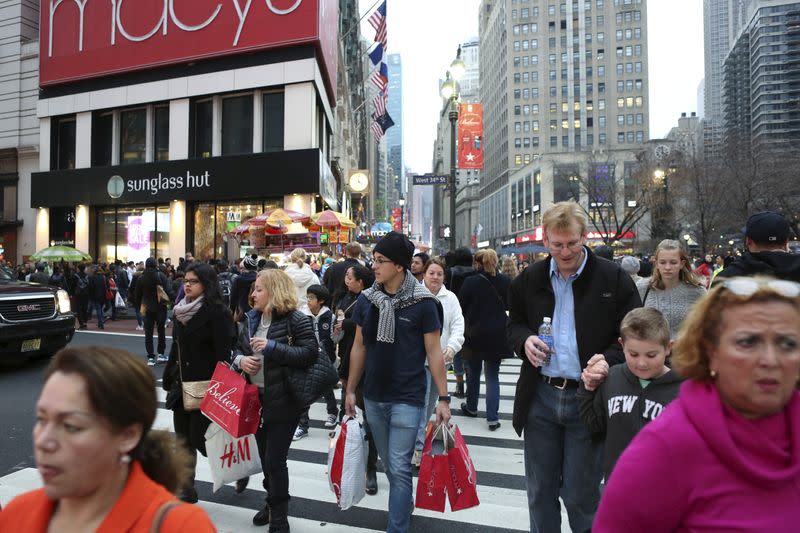 A man in short sleeves carries shopping bags near Herald Square during unseasonably warm weather in Manhattan