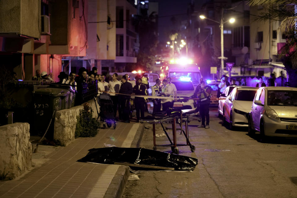 Ultra-Orthodox Jews stand near the covered body of a shooting victim in Bnei Brak, Israel, Tuesday, March 29, 2022. The circumstance of the deadly incident Tuesday were not immediately clear. (AP Photo/Oded Balilty)