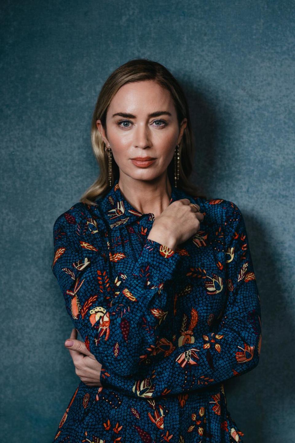 Emily Blunt wears a long-sleeved dress for a portrait.