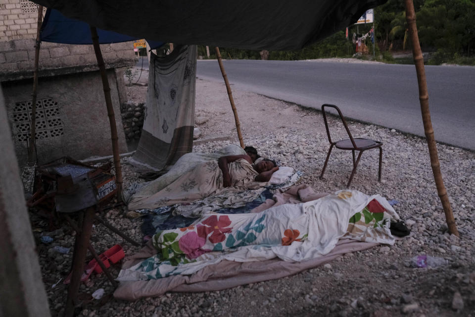 Nurse Gabrielle Lagrenade, center, sleeps next to her daughter on the the side of the road in Les Cayes, Haiti, Monday, Aug. 23, 2021, a week after a 7.2 magnitude earthquake made her rental home unsafe to live in. Lagrenade, 52, describes her current living conditions simply as “inappropriate,” but she continues arriving for her daily shift at the hospital. (AP Photo/Matias Delacroix)