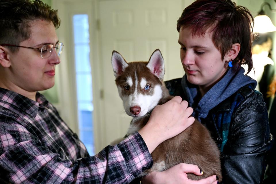 Ellie Wheeler, then 19, left, and sibling Newt, 14, pet their new puppy, Calcifer, on Dec. 9, 2022, at their home in East Lansing.